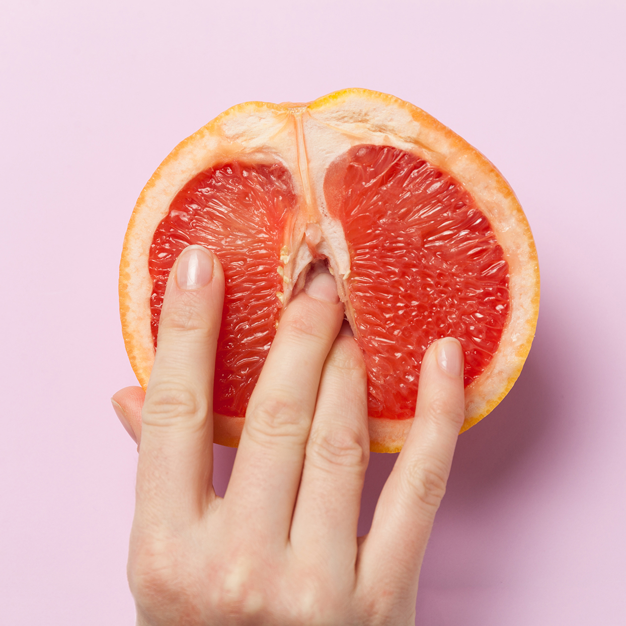 Female Fingers In Grapefruit Half