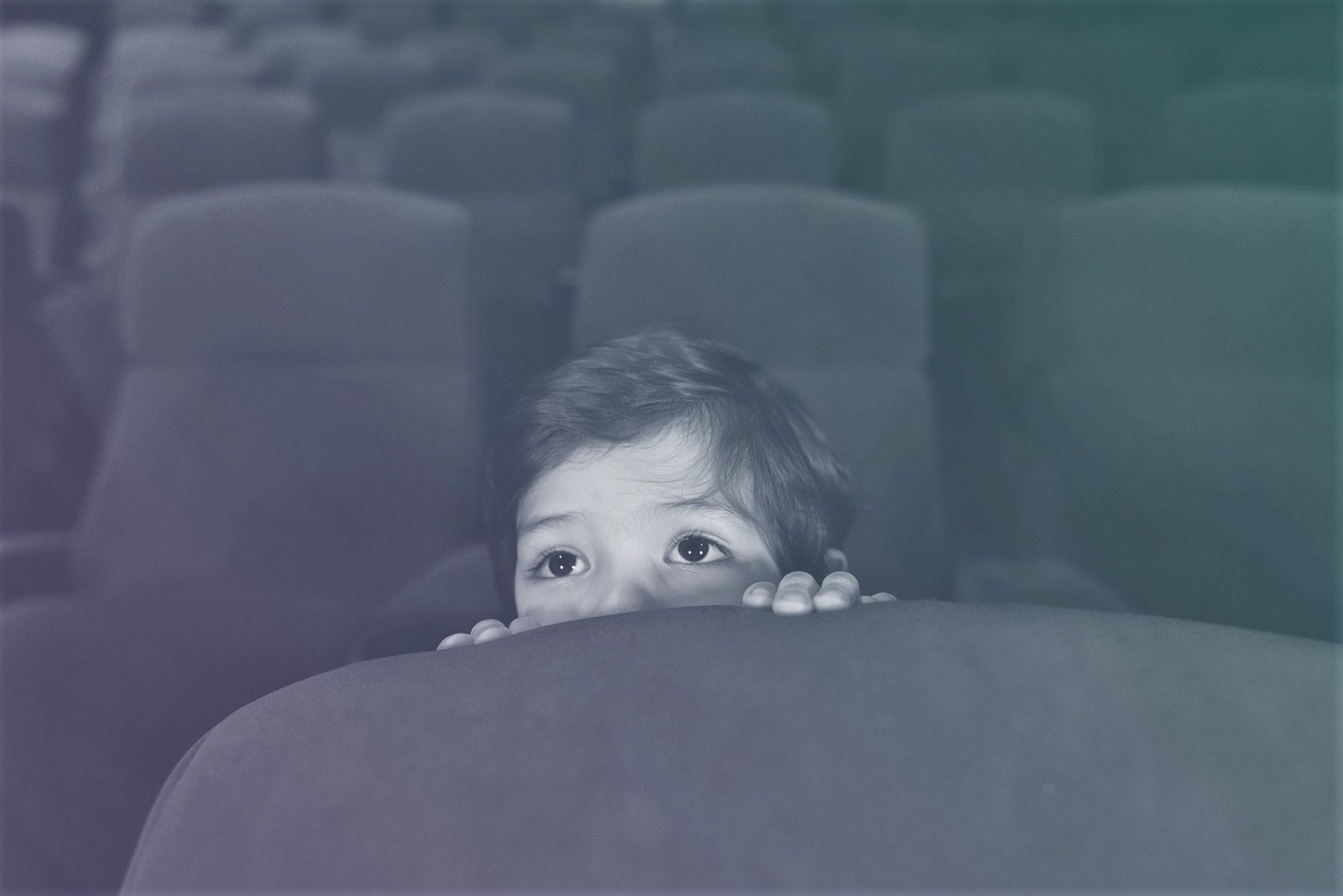 Scared boy watching a movie at the cinema