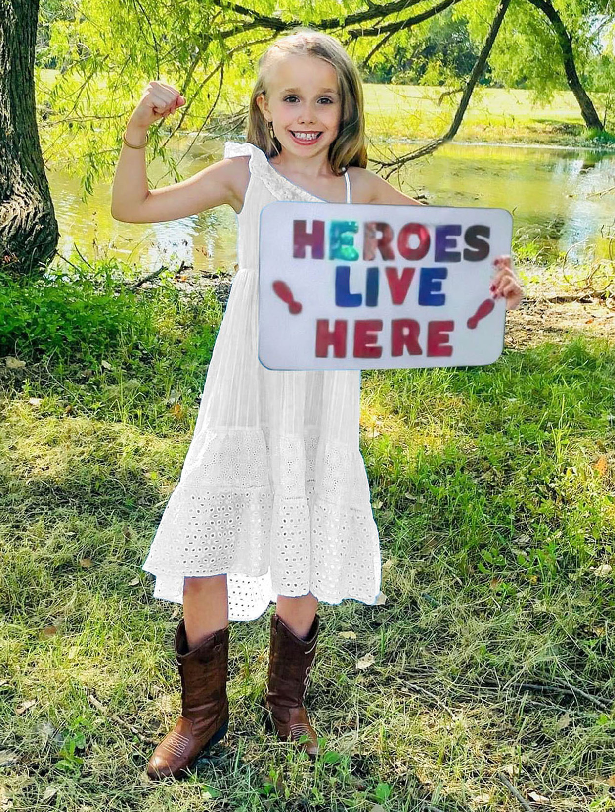 girld holding up heroes live here sign