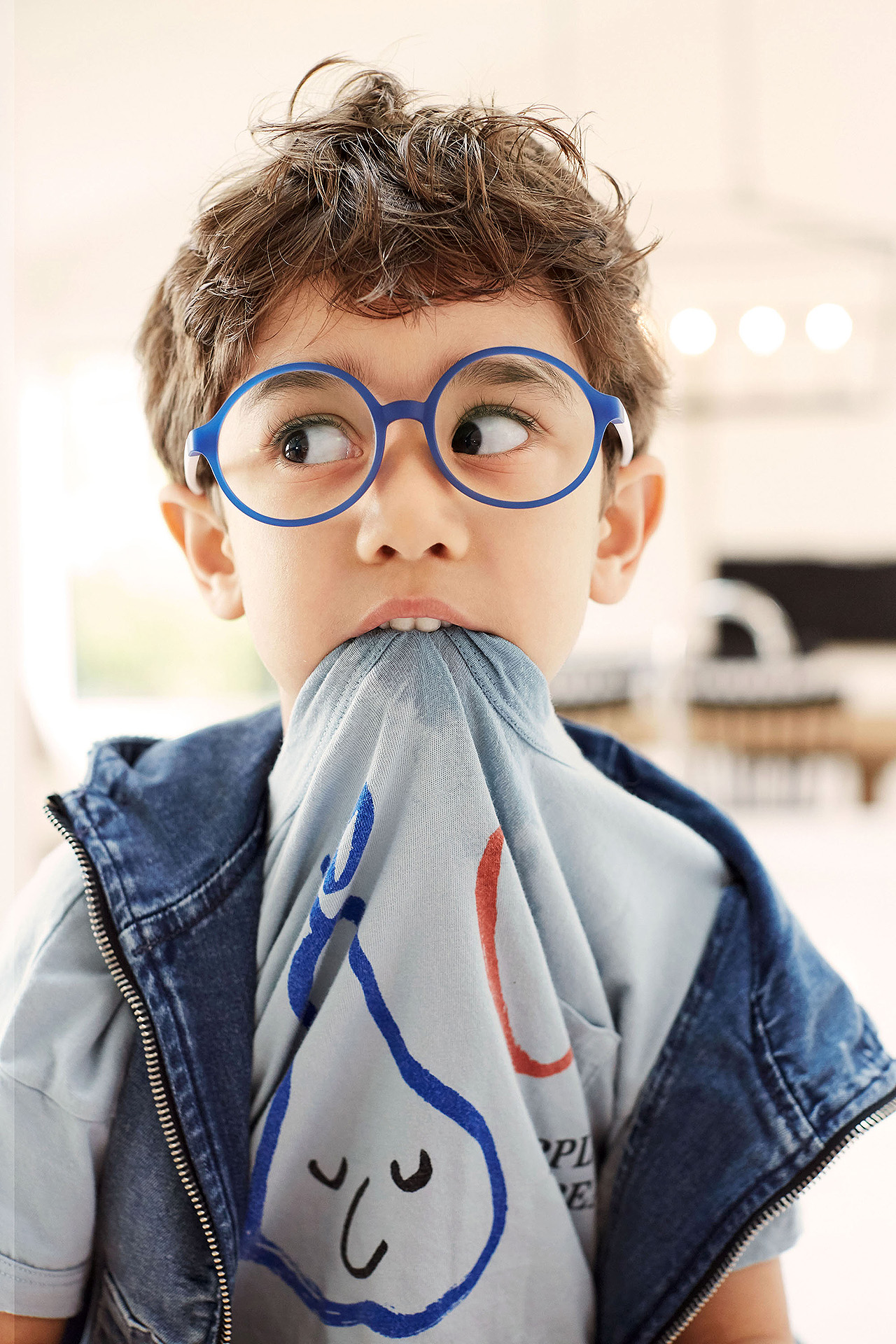 boy in glasses sucking on shirt