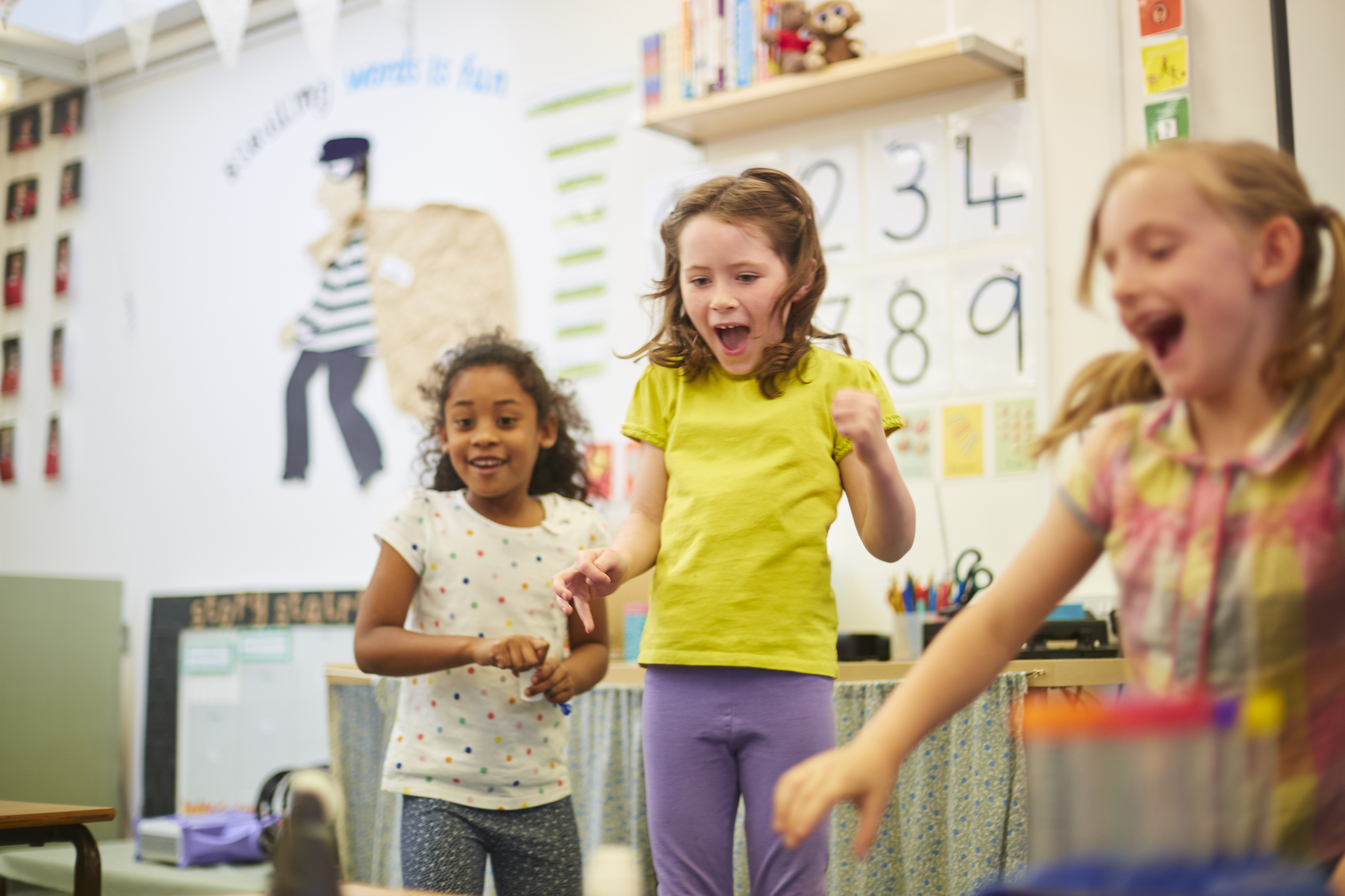 Three Girls Laughing In Elementary School Classroom