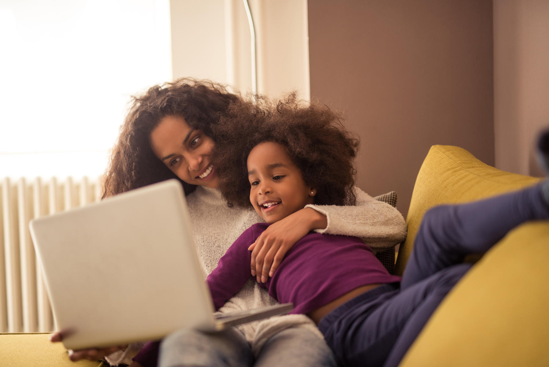 Mother and Daughter Laying On Couch Laughing Watching Laptop Computer Screen