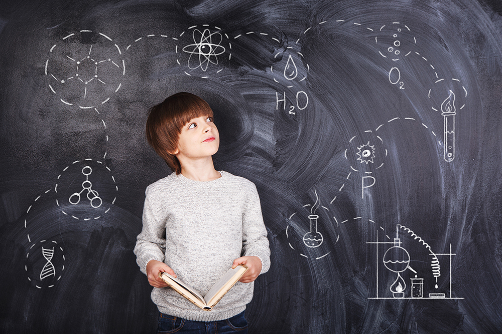 Boy thinking against black chalkboard backdrop