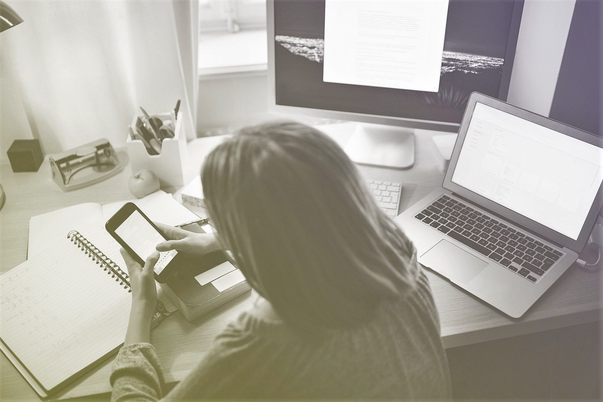 Rear view of girl using smart phone while sitting at illuminated desk