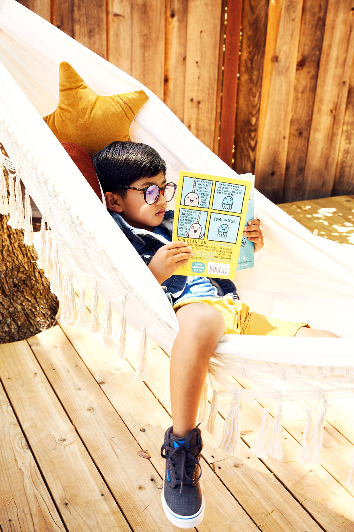 Child reading a book in a hammock