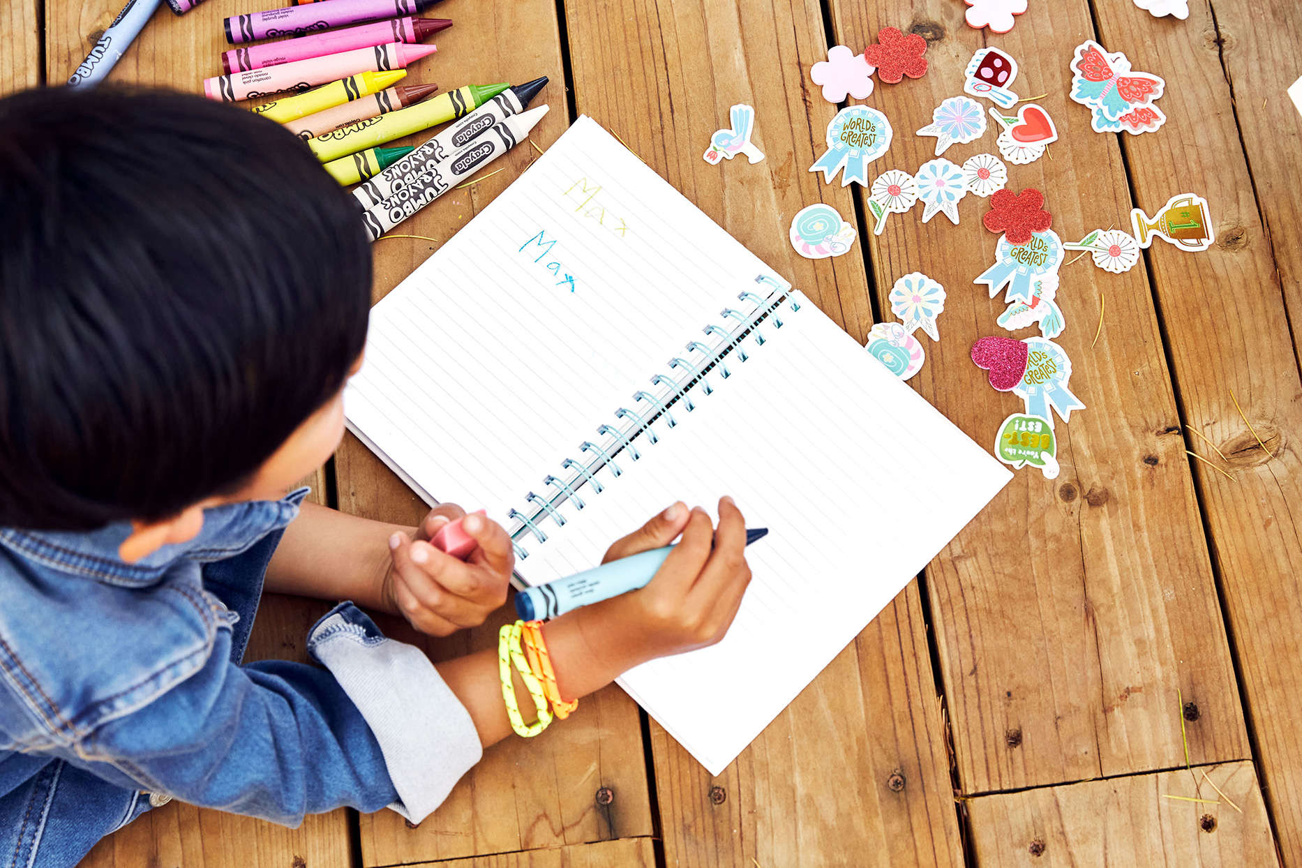 Child writing name with crayons and stickers